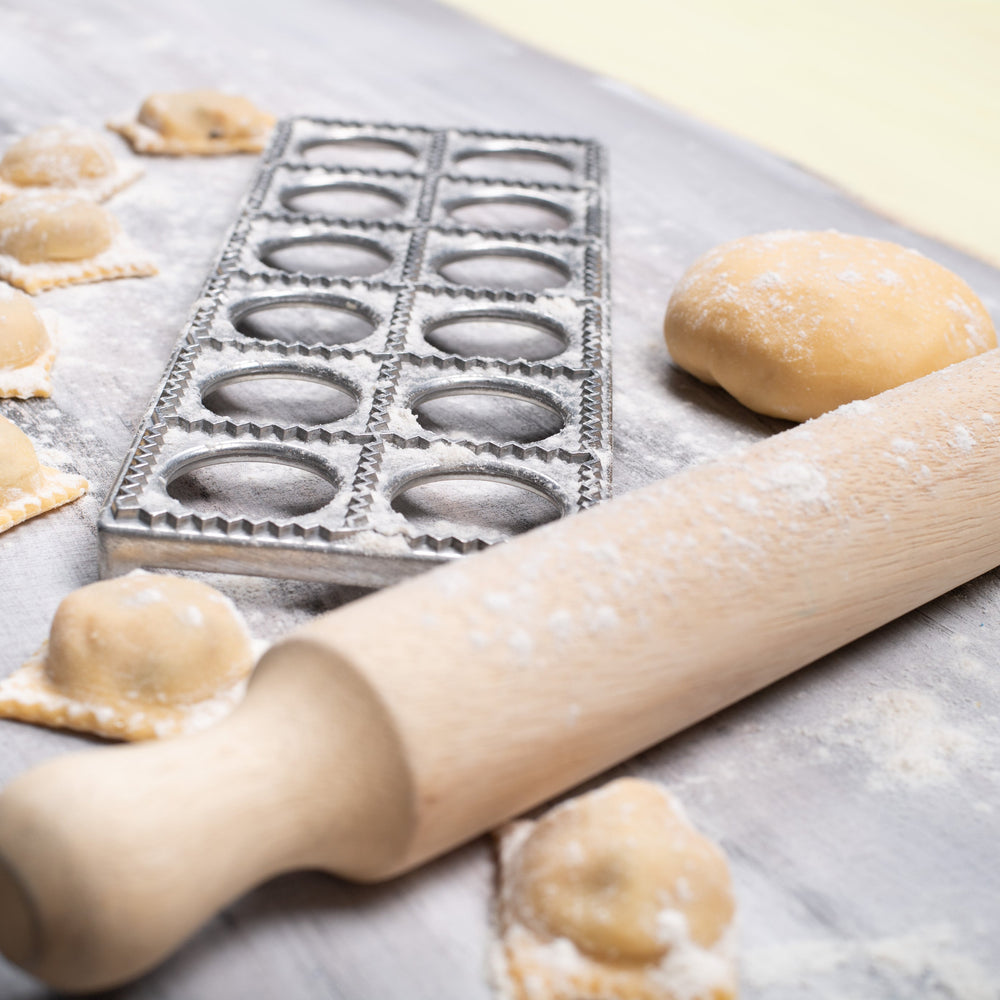 Ravioli making process with a rolling pin and on a floured surface