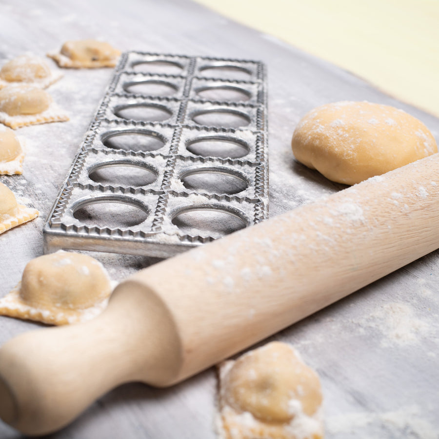 Ravioli making process with a rolling pin and on a floured surface